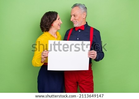 Photo of two aged persons hold demonstrate empty space banner novelty isolated on green color background