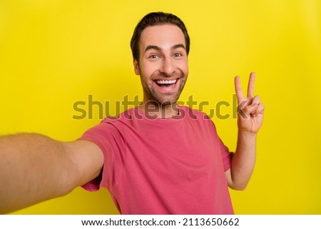 Photo of friendly crazy excited guy show v-sign take self portrait wear pink t-shirt isolated yellow color background