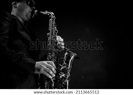 Saxophonist Musician in Black Tuxedo and Bow Tie Plays the Alto Saxophone. Alto Sax Player, Jazz Sazophonist. Black Background. Close-up. Copy Space . High quality photo Royalty-Free Stock Photo #2113665512