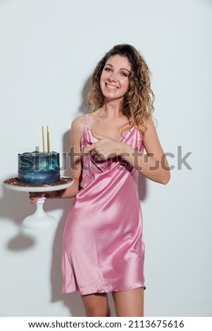 beautiful blonde woman in pink silk dress with sweet cake with candles