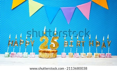 Congratulations on your birthday from the letters of candles number 25 on a blue background with polka dots white copy space. Happy birthday muffin with golden color burning candle for twenty five.