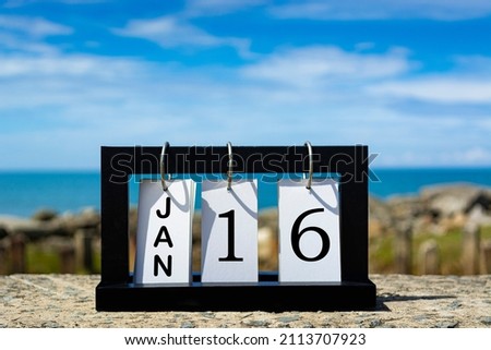 Jan 16 calendar date text on wooden frame with blurred background of ocean. Calendar concept