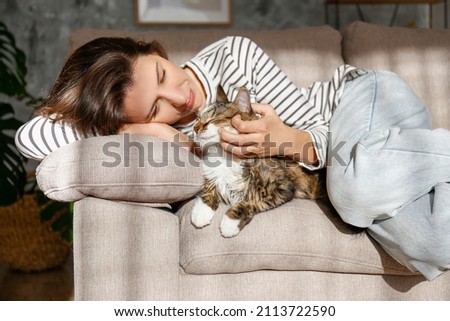 Portrait of young woman holding cute siberian cat with green eyes. Female hugging her cute long hair kitty. Background, copy space, close up. Adorable domestic pet concept. Royalty-Free Stock Photo #2113722590