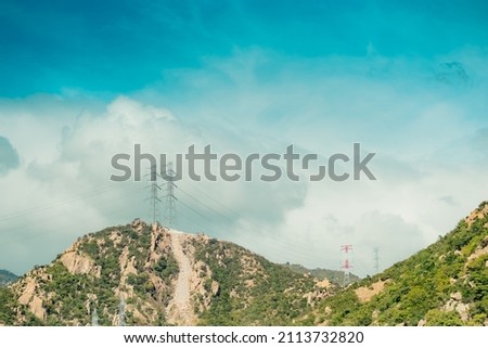 Real nature beauty landscape background. Rocky mountain, bright cloudy Blue sky summer day, high voltage Electricity lines pylons. Sun mood feelings. Power supply remote areas, engineering structures