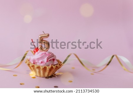 a beautiful picture of a cupcake with pink butter cream and cherry with a number five 5 candle on the top of it. Festive Happy birthday mood. Card design idea. Horisontal