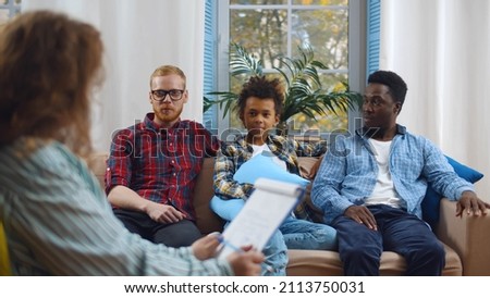 Diverse male gay couple with foster son consulting child protection services worker at home. Woman social worker visiting and inspecting multiethnic gay couple with adopted child Royalty-Free Stock Photo #2113750031