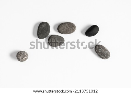 Scattered sea pebble. Smooth gray stones isolated on white background. Flat lay, top view, copy space