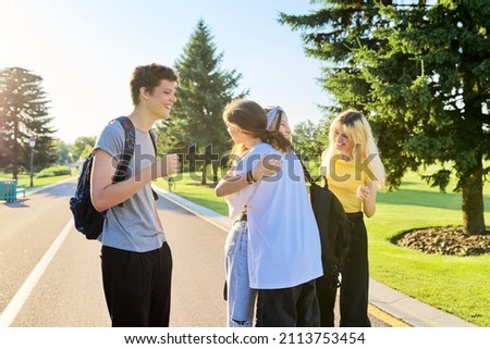 Meeting of smiling teenage friends in a sunny summer park