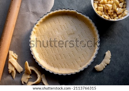 Homemade pie crust in pie plate. Cooking apple pie, dark background Royalty-Free Stock Photo #2113766315