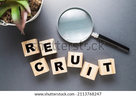 RECRUIT word on alphabet wood cubes with magniffying glass, searching for people, recruitment concept