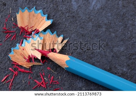 Single coloured pencil sharpened to a fine point with the wooden shavings on a dark background Royalty-Free Stock Photo #2113769873