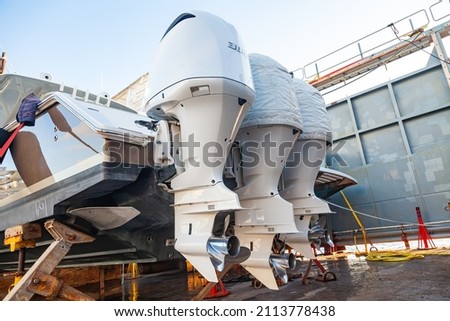 Three outboard motors mounted on a transom mount at the stern of the boat in dry dock. Royalty-Free Stock Photo #2113778438