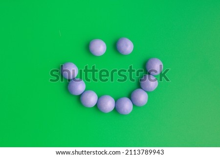 A purple candy smile on a bright green background that makes every child smile and rejoice. Happiness, smile, joy of life, childhood, success, games, round candy.