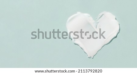 A smear of cosmetic cream in the shape of a heart on a blue background. Royalty-Free Stock Photo #2113792820