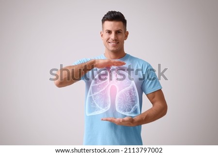 Handsome man holding hands near chest with illustration of lungs on grey background Royalty-Free Stock Photo #2113797002