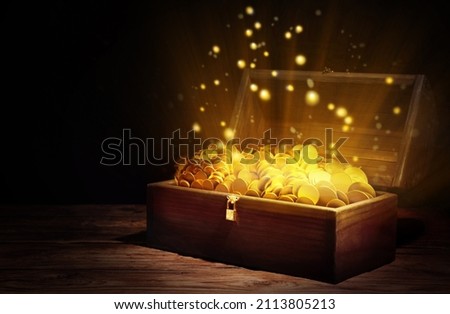 Open treasure chest with gold coins on wooden table against black background Royalty-Free Stock Photo #2113805213