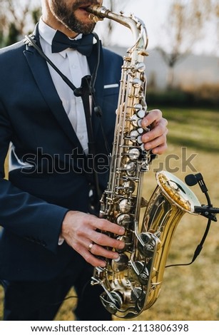 Stylish man in suit, musician, professional saxophonist in suit plays the saxophone. Photography, portrait. Royalty-Free Stock Photo #2113806398