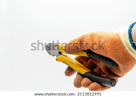 man's hand holding a black and yelow wire cutter. 