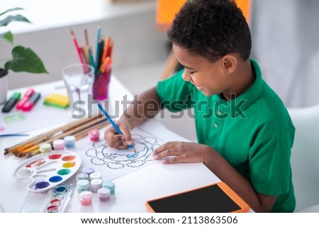 Boy drawing with color pencil sitting at table