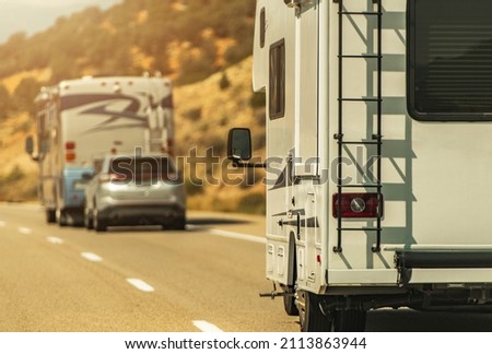 Class C Camper Van and Class A Diesel Pusher Motorhome on a Highway. Summer RV Road Trips. Recreational Vehicles Theme Royalty-Free Stock Photo #2113863944