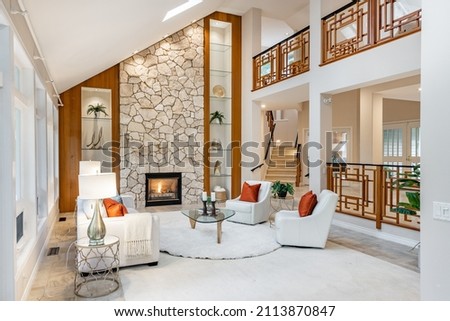Mid century craftsman house interior living room foyer home office with wood panel walls staircase creative wooden railings stone fireplace in warm white tones and orange accent colors Royalty-Free Stock Photo #2113870847