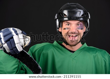 Funny hockey player smiling, bruise around the eye. Black background Royalty-Free Stock Photo #211391155
