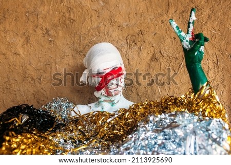 halloween painted clown smiling and showing good sign peace with hand with tinsel decoration