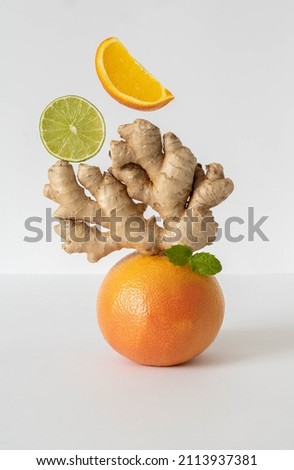 Balancing fruits and vegetables on the table. Equilibrium floating food balance. Fruits levitating on the table: grapefruit, lime, ginger, mint. Pyramid of fruits on a white background.