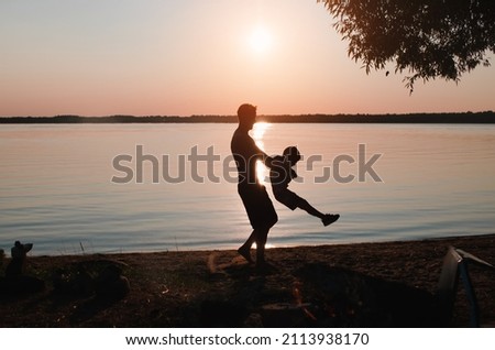 Happy family, father and son having fun together on beach at sunset in nature. Side view of dad holding child in arms against sky outdoors. Fatherhood, childhood.