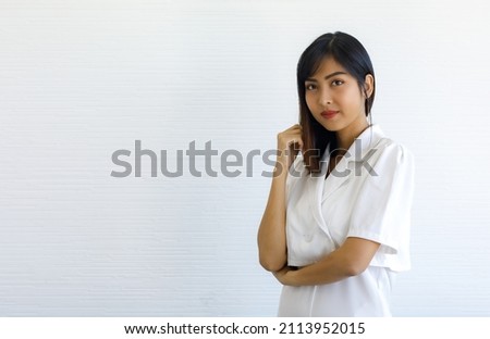 Portrait studio shot of Asian young happy beautiful long hair female businesswoman entrepreneur in white outfit stand crossed arm posing smiling look at camera in front wall background with copyspace.