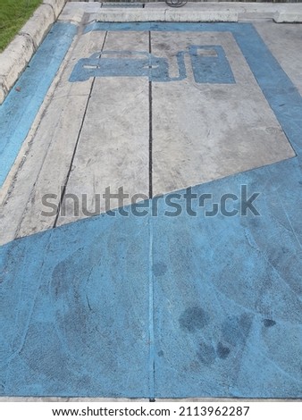 Concrete floor is painted in blue and white with pictures of cars and square vans indicating a parking spot for inflating tires.