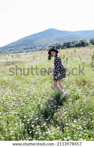 woman walks through a field with flowers