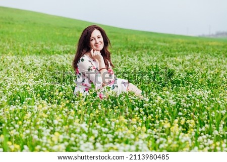 a beautiful woman in a dress with wyhets on a green meadow field