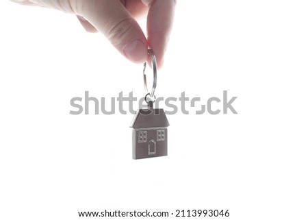metal keychain in the form of a house in a female hand, close-up