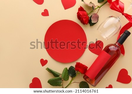 Composition with blank card, bottle of wine, glass and flowers on color background. Valentine's Day celebration