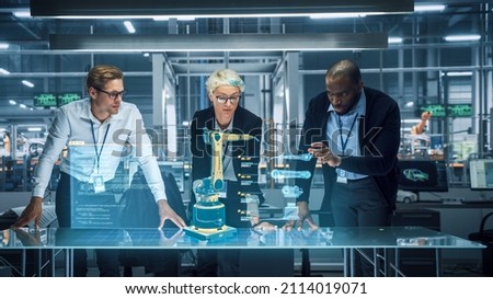 Industry 4.0 High-Tech Factory: Diverse Team of Robotics Engineers Working on Robot Arm Design, Using Augmented Reality Hologram to Manipulate 3D Model by Gestures. Engineering with Digital Technology Royalty-Free Stock Photo #2114019071