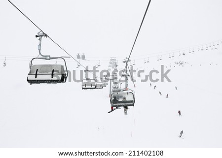 Ski season in the Alps. Panorama of the ski lifts during snowfall and fog. Picture taken in Austrian Alps