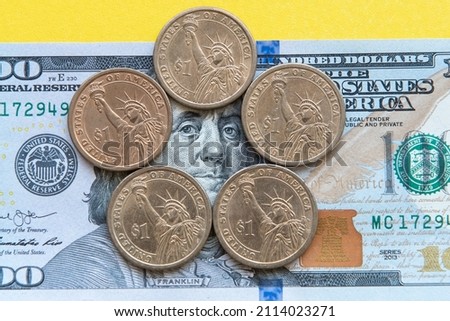 one dollar coins around a portrait of Franklin on a hundred dollar bill