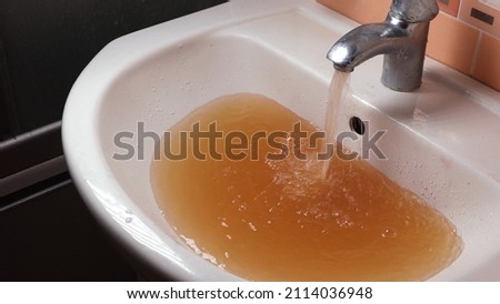 Rusty Water Pours From Tap. Water Pollution. Global Environment. Rusty Water Pours From Tap. Water Pollution. Global Environment. Royalty-Free Stock Photo #2114036948