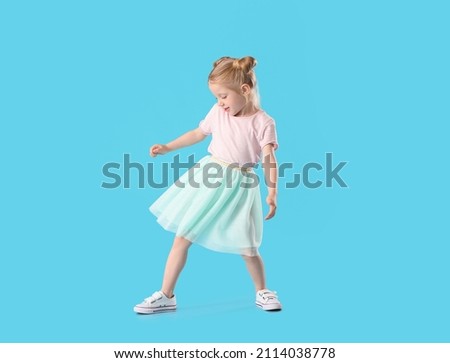 Cute little girl in skirt dancing on blue background
