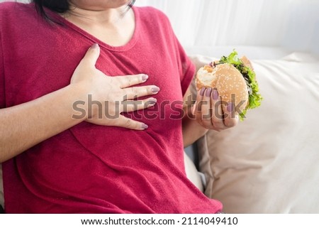 woman having Gastroesophageal reflux disease after eating a burger Royalty-Free Stock Photo #2114049410
