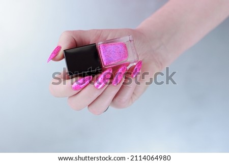 Female hands with long nails and neon pink nail polish