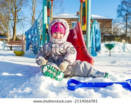 a small child plays on the playground with snow.