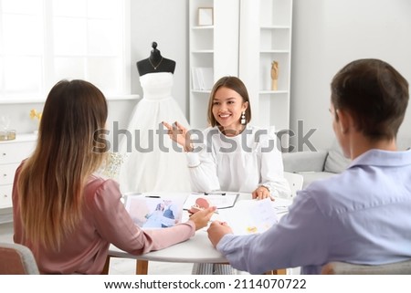 Female wedding planner discussing ceremony with clients in office Royalty-Free Stock Photo #2114070722