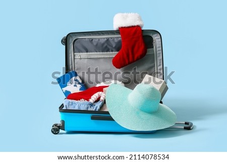 Open suitcase with Christmas socks and things on blue background