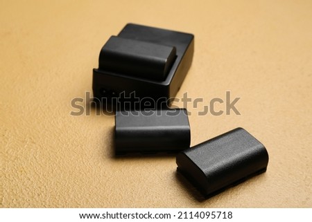 Camera batteries and charger on beige table background