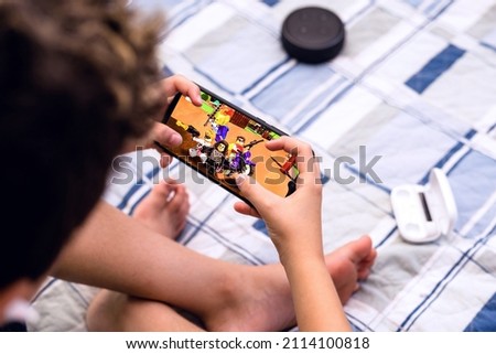 young boy with mobile game, kid using smartphone for online games, and electronic gadgets around, spot focus