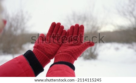 Closeup view stock photography of two female hands in red gloves isolated on white snow background. Woman holding both empty palms making cupped gesture with her outstretched arms 