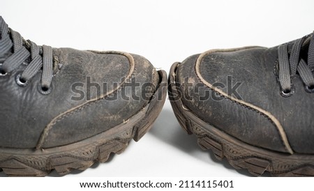 Close-up view stock photogrphy of damaged male old worn torn black leather shoes with holes and scratches