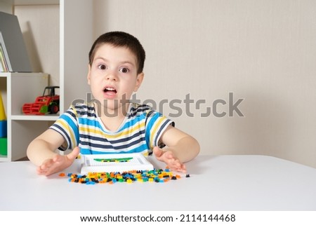 A boy of 4 years old plays with a mosaic, collects a picture from small plastic parts. Development of fine motor skills in children